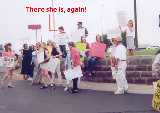 A photograph of the protest in Ardmore in May 2003. She's standing holding a protest sign.