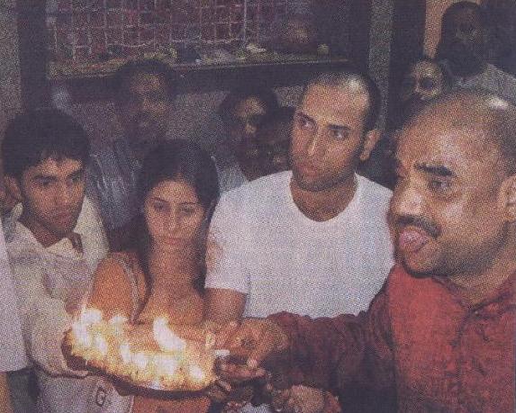 Indian cricket sportmen, members of the public and a Hindu priest (foreground) performing Aarti of an unshown idol in an unnamed temple in the city of Indore, Central India